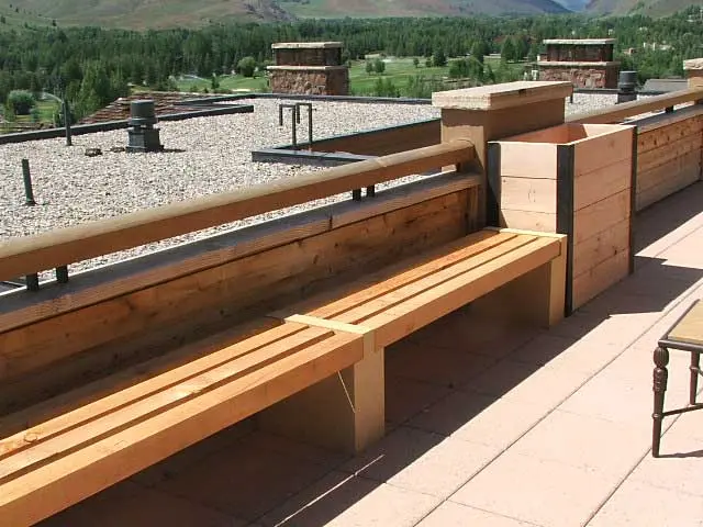 image shows a rooftop setting with wooden benches and planters
